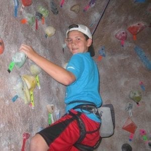 boy rock climbing looking at camera